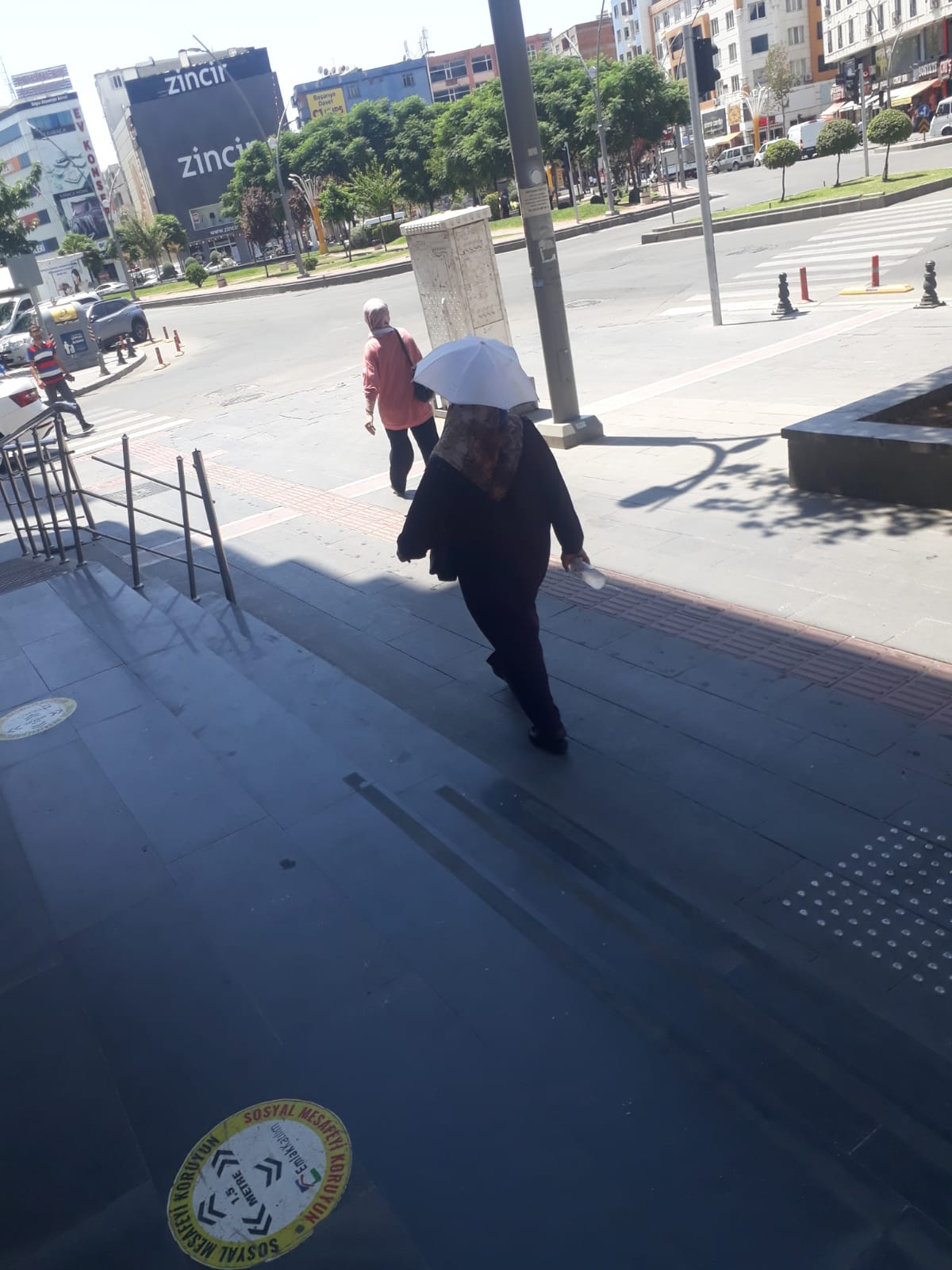 Başına şemsiye tutturarak güneşten korundu